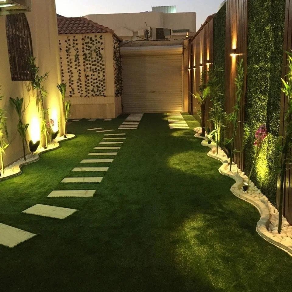 ممر إضاءة ليلية بين مسطحات العشب الصناعي