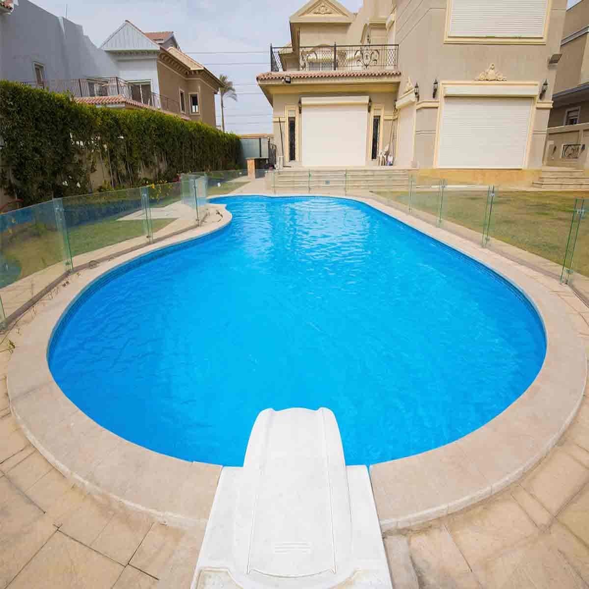 مسبح بيضاوي بسياج زجاجي أمام فيلا سكنية